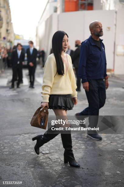 Taeyeon wears a pastel yellow low-neck v-neck pullover, a black ruffled / pleated mini skirt, a brown monogram leather bag from Vuitton, knee high...