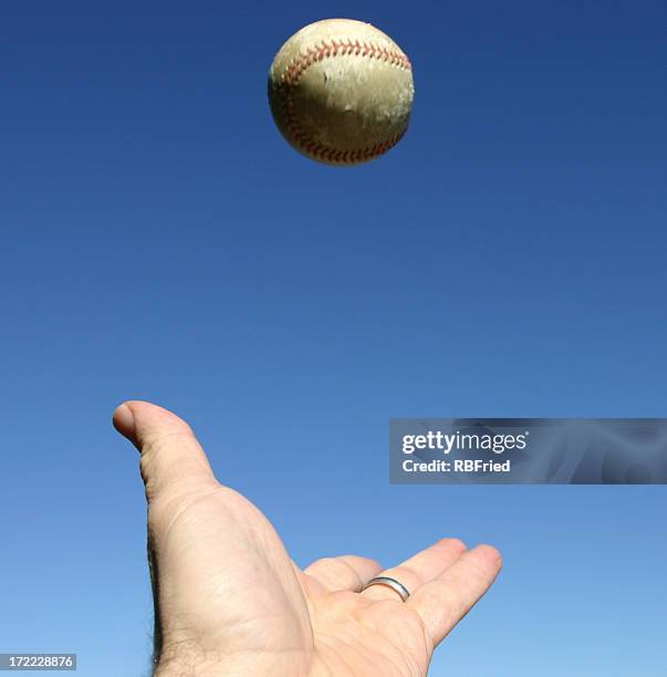 close-up of hand trying to catch a ball in the sky - baseball thrower stock pictures, royalty-free photos & images