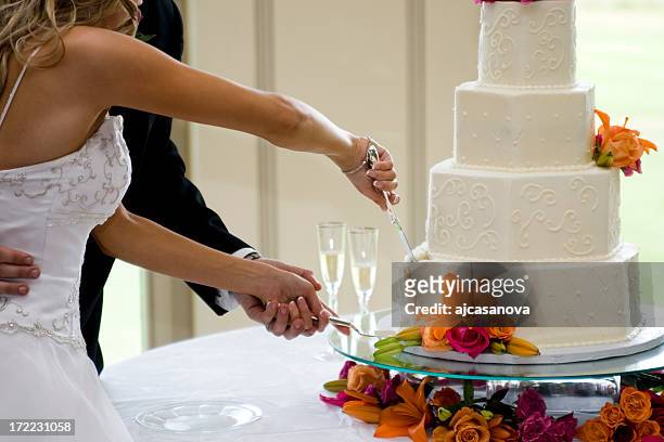 newly-married couple cutting wedding cake together - wedding cake cutting stockfoto's en -beelden
