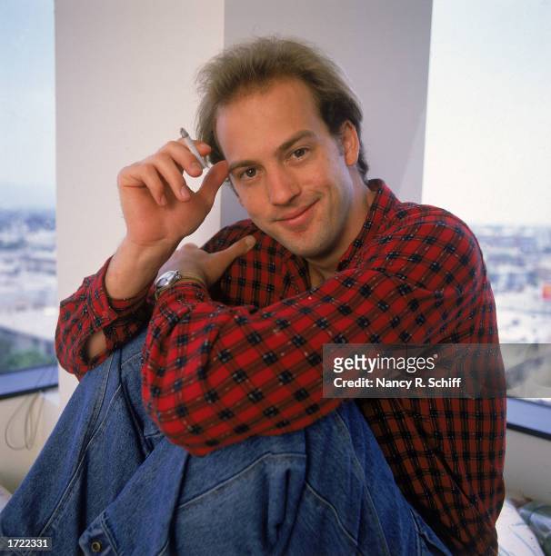 Portrait of American actor Anthony Edwards sitting and holding a cigarette, 1989.