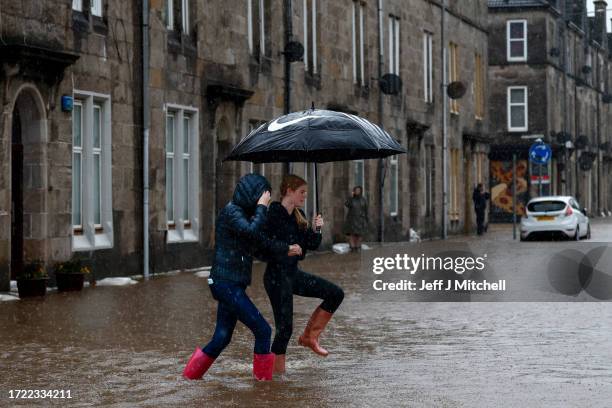 Members of the public struggle with flooding as torrential rain continues on October 07, 2023 in Dumbarton, United Kingdom. The UK is experiencing...