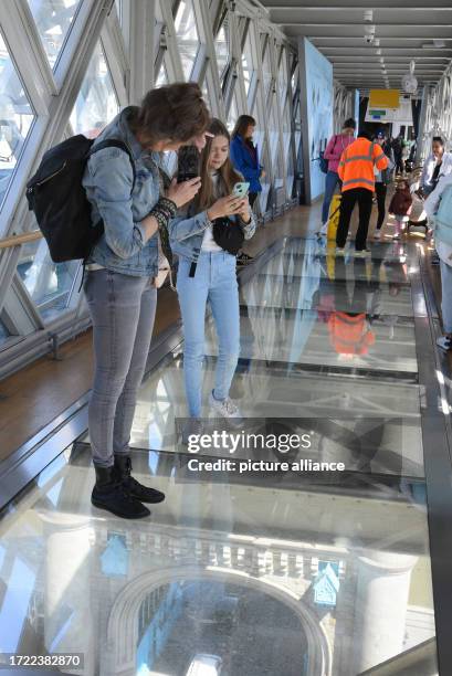 May 2022, Great Britain, London: In London's Tower Bridge, one of the city's landmarks, visitors photograph the view from a glass walkway down into...