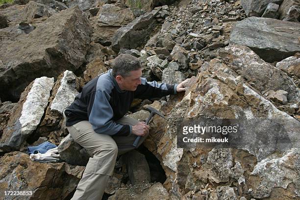 geologe wissenschaftler mann schaut am rock in quarry - geologie stock-fotos und bilder