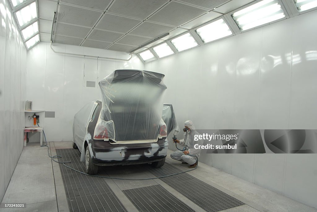 Man in white garage painting automobile