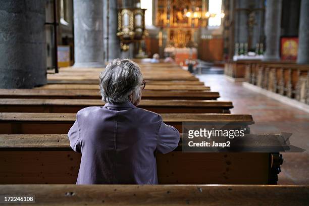 vecchia donna pregare in una chiesa quasi vuota, vista posteriore - pregare foto e immagini stock
