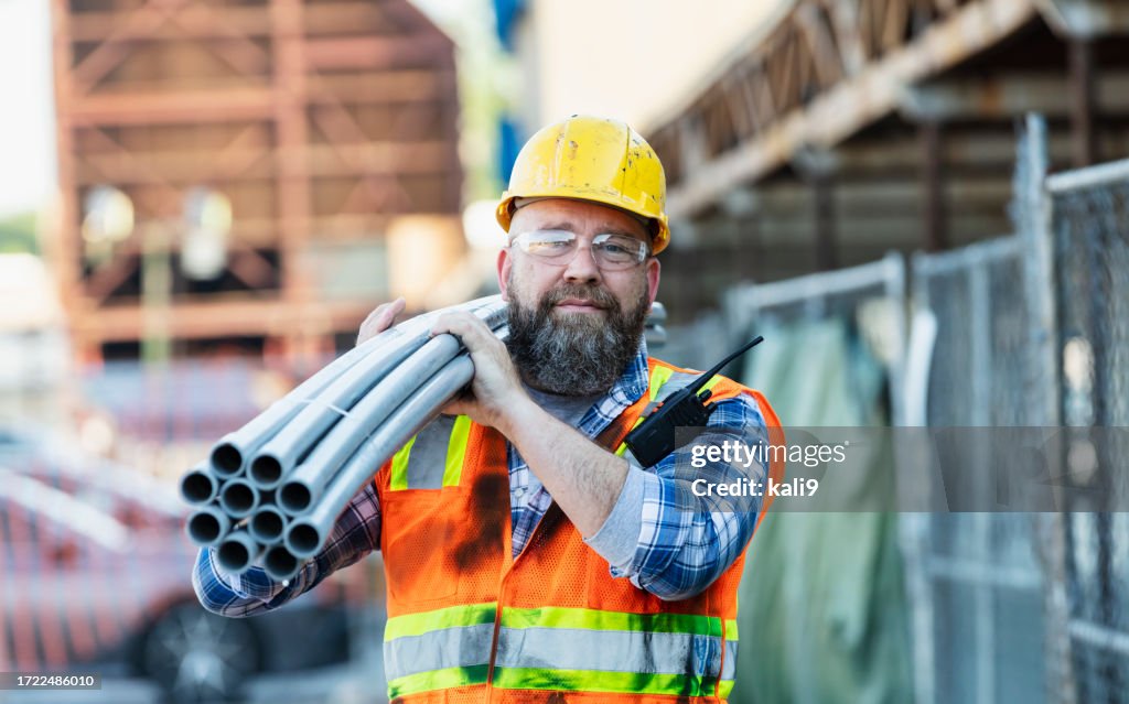 Trabajador de la construcción llevando pipas en hombro
