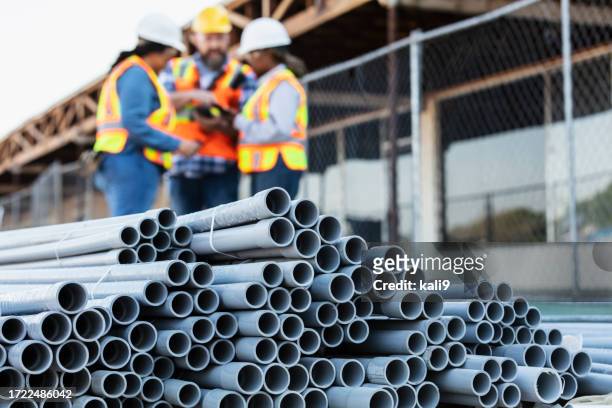 pvc pipes at construction site, workers in background - pvc stock pictures, royalty-free photos & images