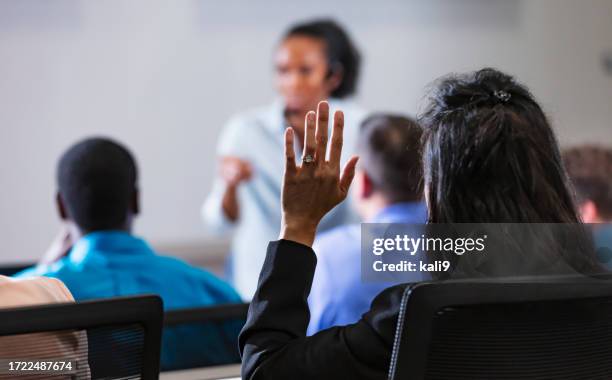 asian woman raises hand during q and a session - vragen en antwoorden stockfoto's en -beelden