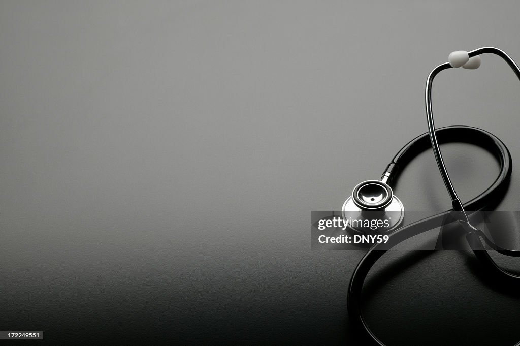 Elegantly coiled stethoscope on dark gray background