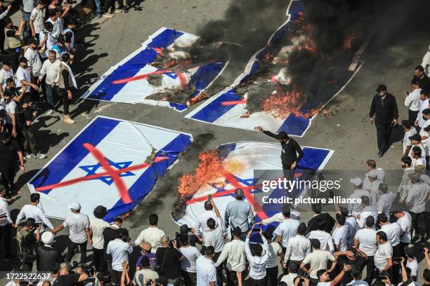 October 2023, Iraq, Baghdad: Thousands of followers of influential Iraqi cleric Moqtada al-Sadr burn Israeli flags as they part in a rally at Tahrir...