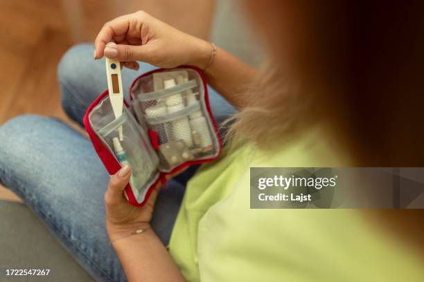 an unrecognizable woman takes out a thermometer from the first aid kit at home - model kit stock pictures, royalty-free photos & images