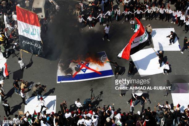 Protesters burn an Israeli flag during a demonstration at Tahrir Square in Baghdad on October 13 amid the ongoing battles between Israel and...