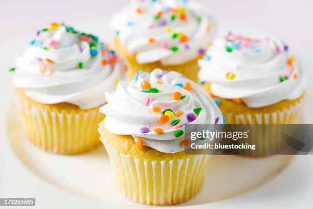 four yellow cake and white frosted cupcakes with confetti - gekleurde hagelslag stockfoto's en -beelden