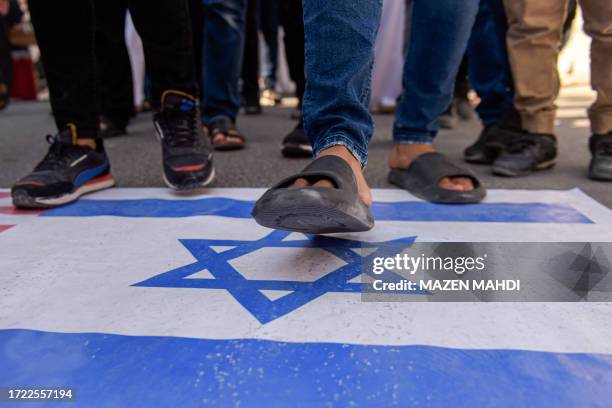 Man walks on a depiction of the Israeli flag during a protest in Manama on October 13 as thousands of protesters poured onto the streets of several...