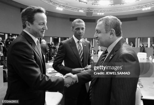 Editors note------B&W version------- US President Barack Obama looks on as British Prime Minister David Cameron shakes hands with Egyptian Prime...