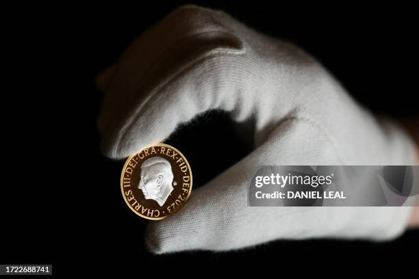 An assistant holds up a £2 coin during a photocall to unveil eight new designs that are set to appear on UK coins, at the Royal Mint, in London on...