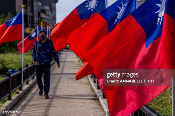 Man walks past the Taiwan's national flags on Nangan island in Taiwan's Matsu Islands on October 13, 2023.