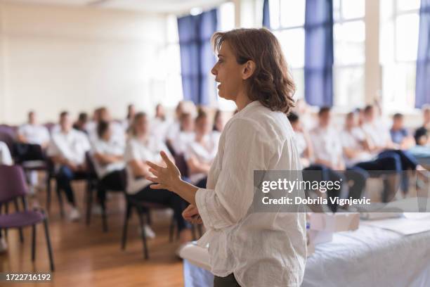 woman talking in a classroom full of students - direitos da mulher imagens e fotografias de stock