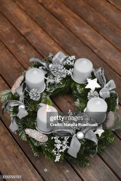 first candle being lit on the first advent sunday. adventskranz with four candles on wooden background.. - adventskranz stock-fotos und bilder