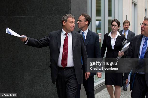 Ian Hannam, former global chairman of equity capital markets at JPMorgan Chase & Co., left, holds paperwork as he arrives to give evidence at the...
