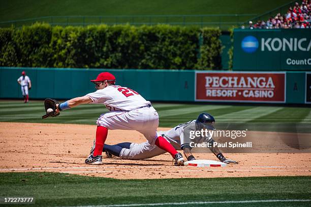 Ichiro Suzuki of the New York Yankees dives back to first base on a pickoff attempt to Brendan Harris of the Los Angeles Angels of Anaheim during the...