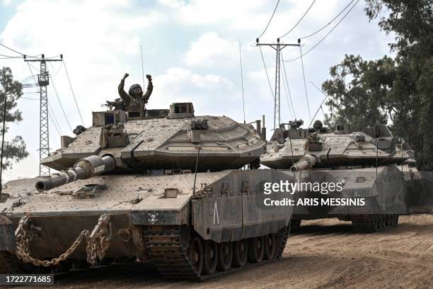 Graphic content / An Israeli soldier gestures from the turret of a Merkava battle tank, as it deploys along the border with the Gaza Strip in...