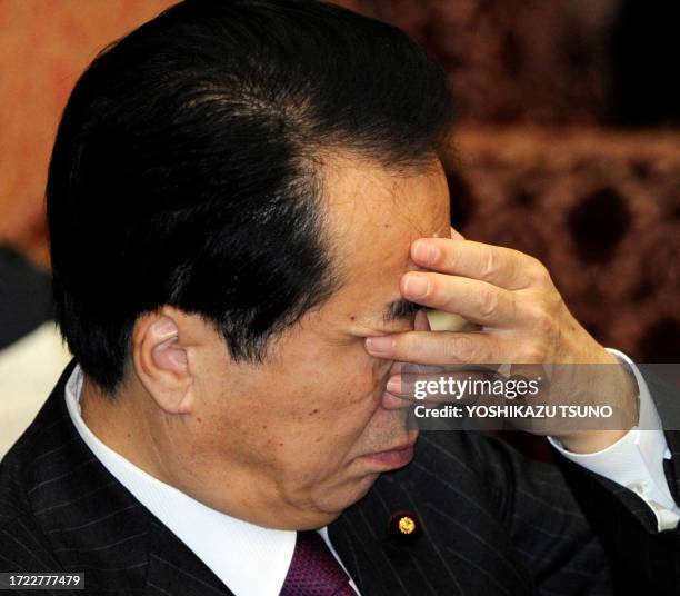 Japanese Prime Minister Naoto Kan covers his face with his hand during the Upper House's budget committee session at the National Diet in Tokyo on...