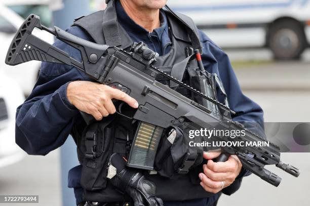 Police officer holds an HK G36 assault rifle as he stands guard near the Gambetta high school in Arras, northeastern France on October 13 after a...