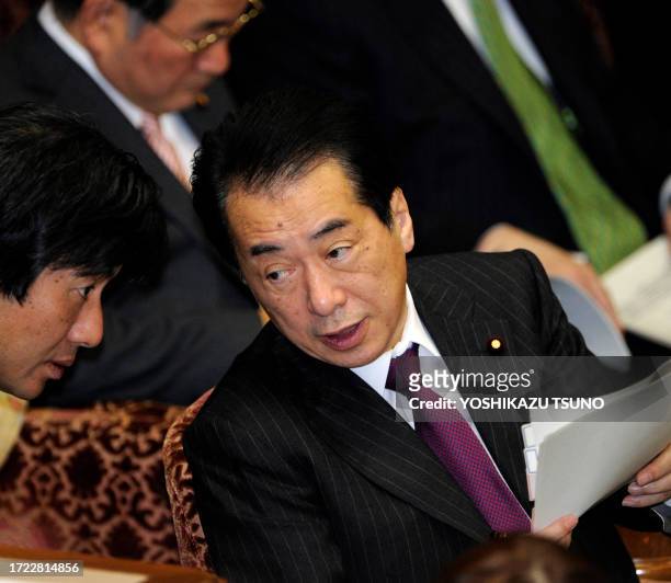 Japanese Prime Minister Naoto Kan chats with his aide during the upper house's budget committee session at the National Diet in Tokyo on March 7 one...