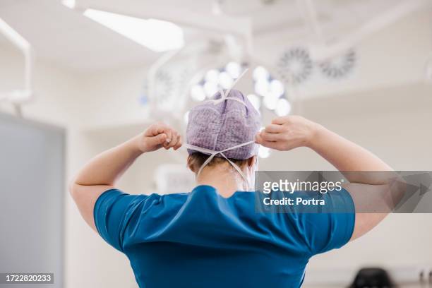 chirurgin bindet chirurgische maske im operationssaal des krankenhauses - chirurgenkappe stock-fotos und bilder