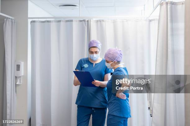 arzt und krankenschwester überprüfen medizinische berichte auf der intensivstation des krankenhauses - intensivmedizin stock-fotos und bilder