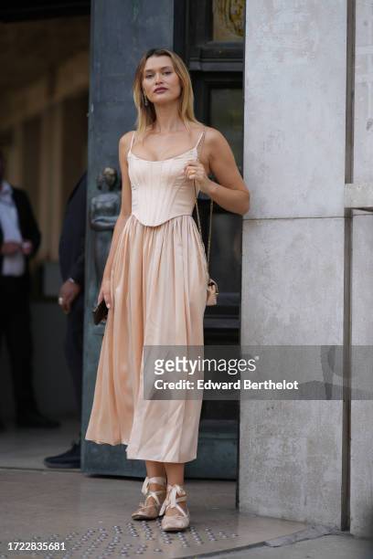 Guest wears a corset / top in white, a pastel pale pink gathered midi skirt, ballerina shoes, outside Zimmermann, during the Womenswear Spring/Summer...