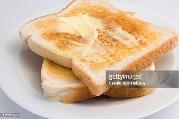 freshly toasted bread smothered in creamy butter - geroosterd brood stockfoto's en -beelden
