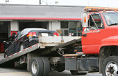 Black car on a red flat bed tow truck