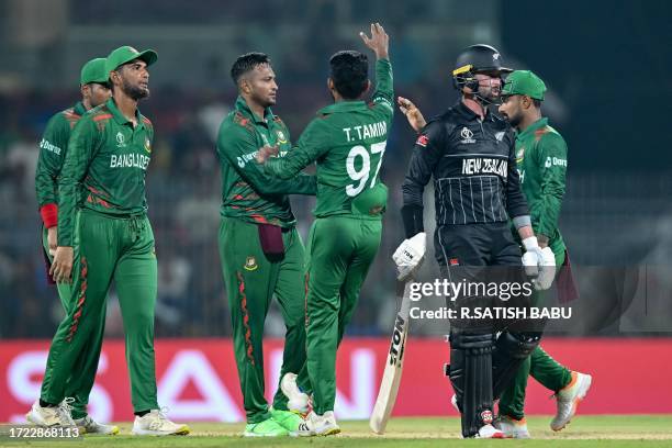 Bangladesh's captain Shakib Al Hasan celebrates with teammates after taking the wicket of New Zealand's Devon Conway during the 2023 ICC Men's...