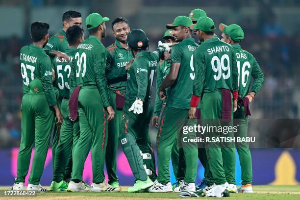 Bangladesh's captain Shakib Al Hasan celebrates with teammates after taking the wicket of New Zealand's Devon Conway during the 2023 ICC Men's...