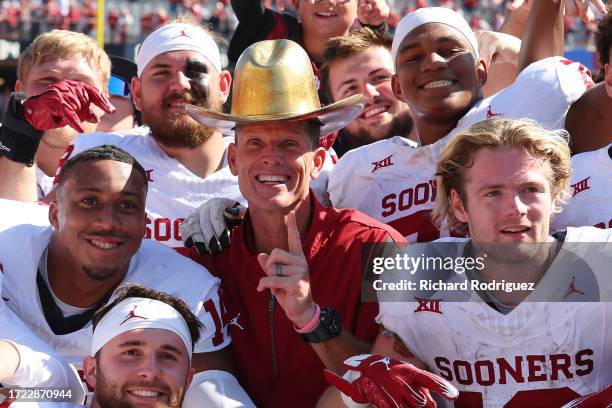 Head coach Brent Venables of the Oklahoma Sooners wears the Golden Hat as he poses for a group photo with the team at the Cotton Bowl on October 07,...