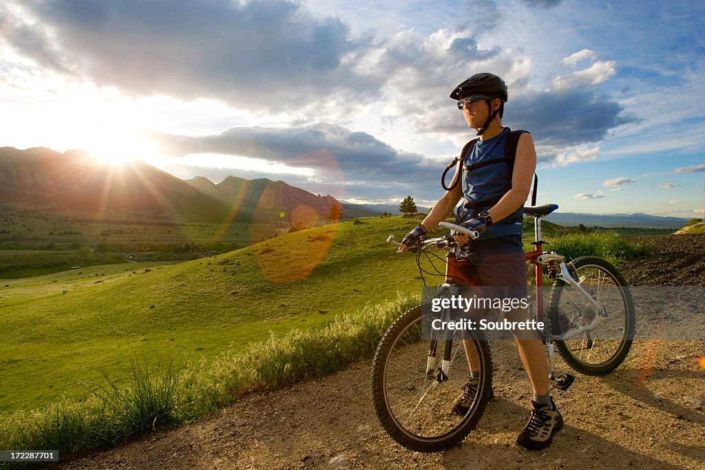 A man standing in a dirt road with a bike