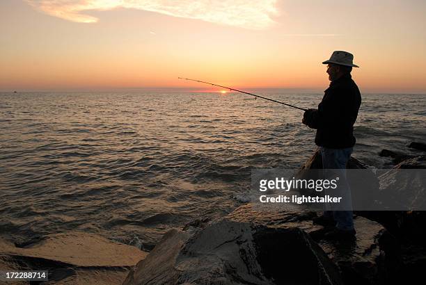 silhouette of a fisherman during sunrise on lake michigan - lake michigan stock pictures, royalty-free photos & images