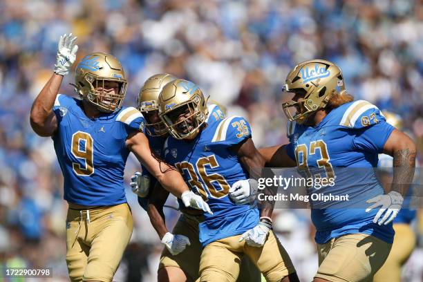 Alex Johnson of the UCLA Bruins celebrates with Choe Bryant-Strother and Jay Toia after intercepting the ball against the Washington State Cougars in...