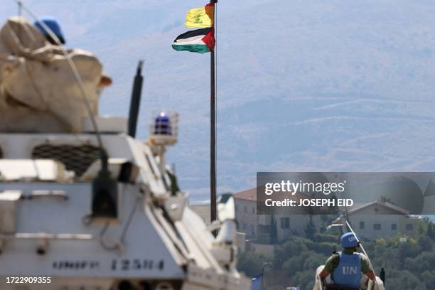 The Palestinian flag and the flag of Hezbollah wave in the wind on a pole as peacekeepers from the United Nations Interim Force in Lebanon patrol the...