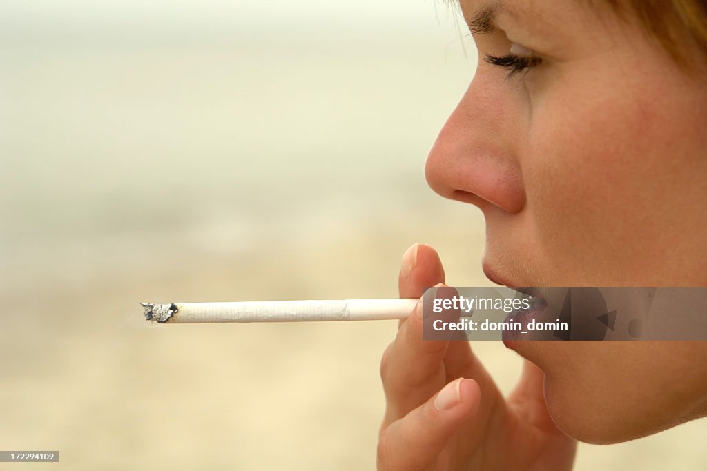 Close-up of woman's face smoking slim cigarette