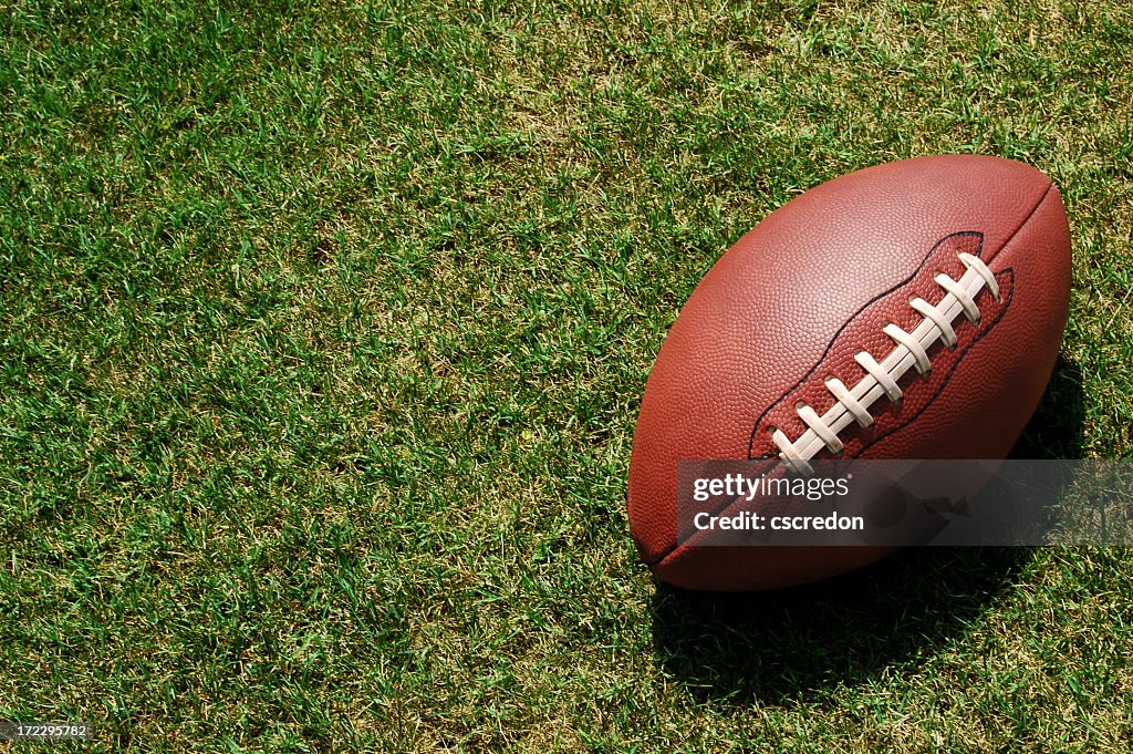 A lone football resting in the green grass