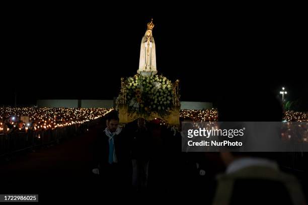 Pilgrims holding candles pray during the candle procession at the Sanctuary of Fatima, on the anniversary of the international pilgrimage, with the...