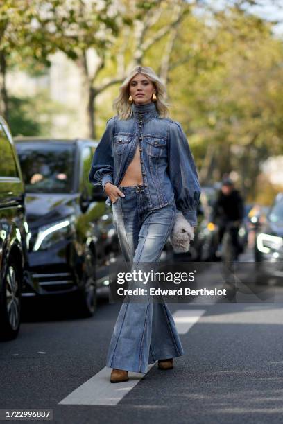 Devon Windsor wears a blue turtleneck denim jacket with puff sleeves, blue flared denim jeans pants, a white fluffy bag, outside Zimmermann, during...