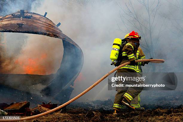 full geared firefighter with water hose on field - wildfire firefighter stock pictures, royalty-free photos & images