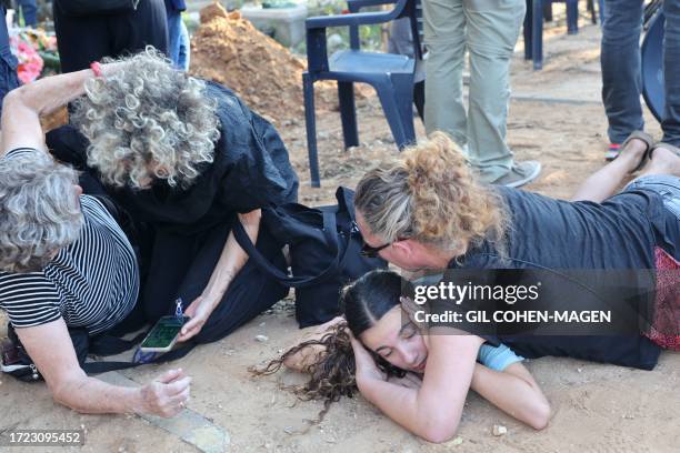 Mourners duck for cover upon hearing sirens warning of incoming rockets during the funeral of Tom Godo, killed during the attack by Palestinian Hamas...