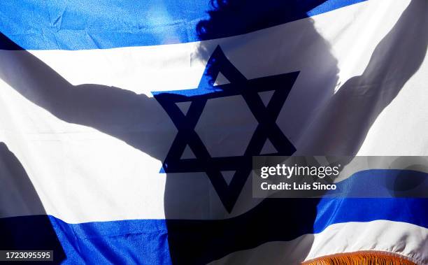 Los Angeles, CA - A supporter of Israel carries a flag through ba crowd of students rallying on the UCLA campus in support of Palestinians caught up...