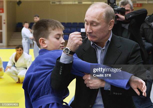 Russia's Prime Minister Vladimir Putin shows a hold to a young judo wrestler at the Regional Judo Center at the Arena Sports Complex in the Siberian...