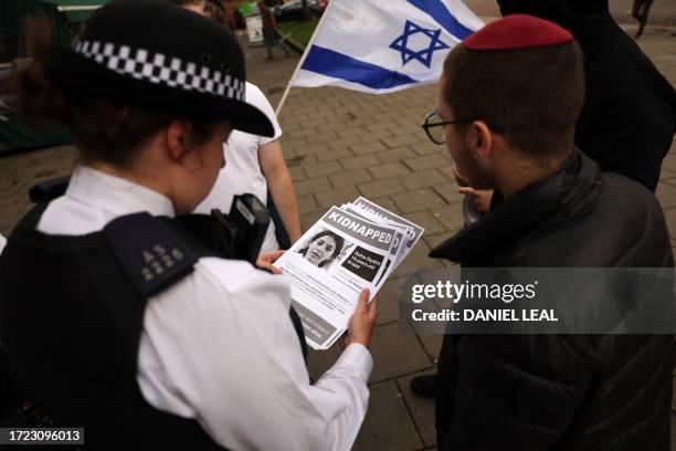 Group of young Jewish men speak with police officers as they put up posters showing recently kidnapped or missing Israelis after the Hamas attack in...